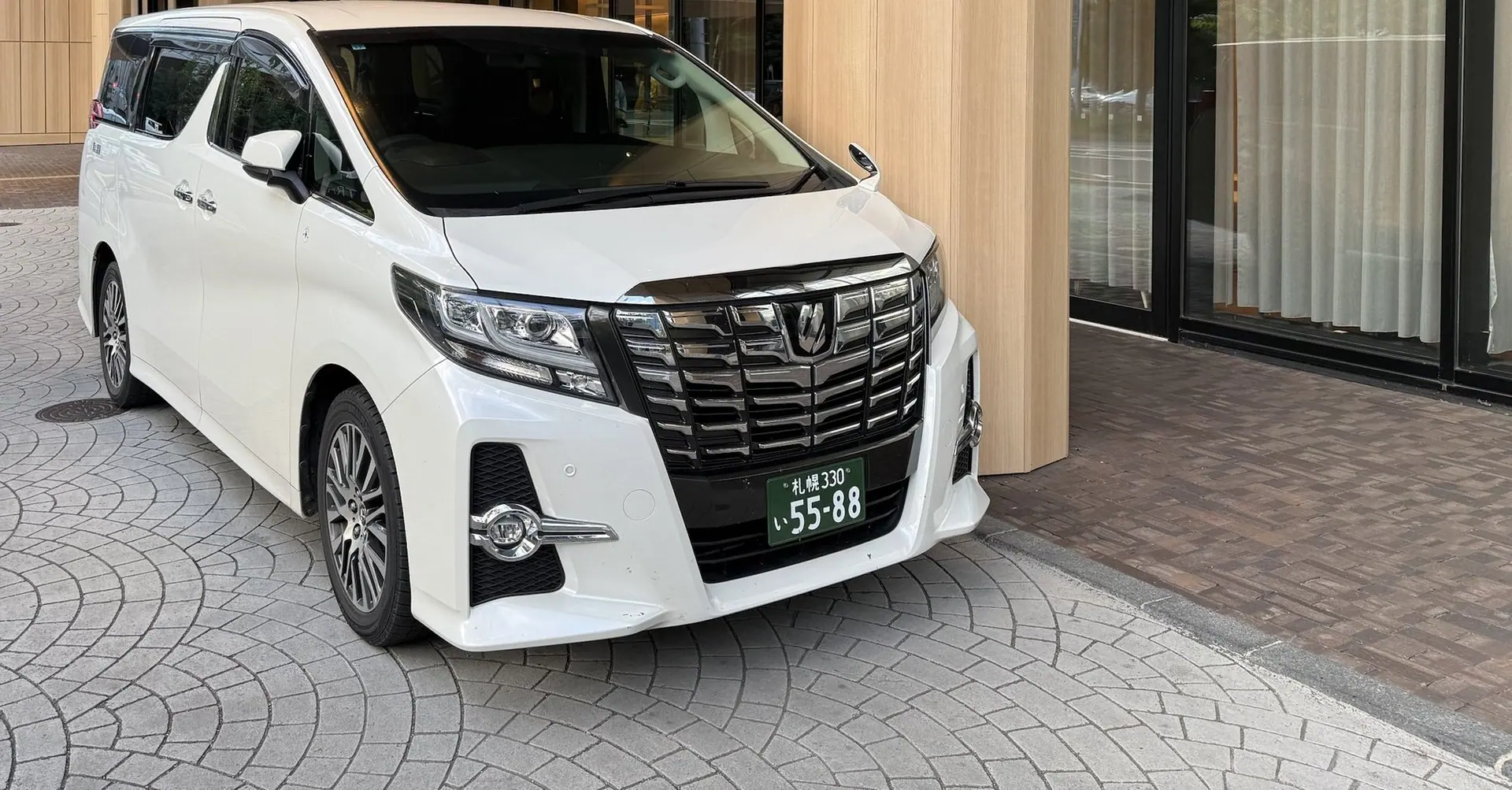 White Toyota Alphard beneath a hotel entrance canopy in Hokkaido