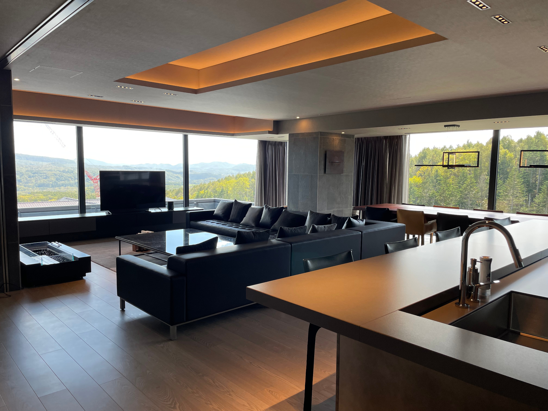 Penthouse living room overlooking the Hokkaido forest, with fireplace and long sofa