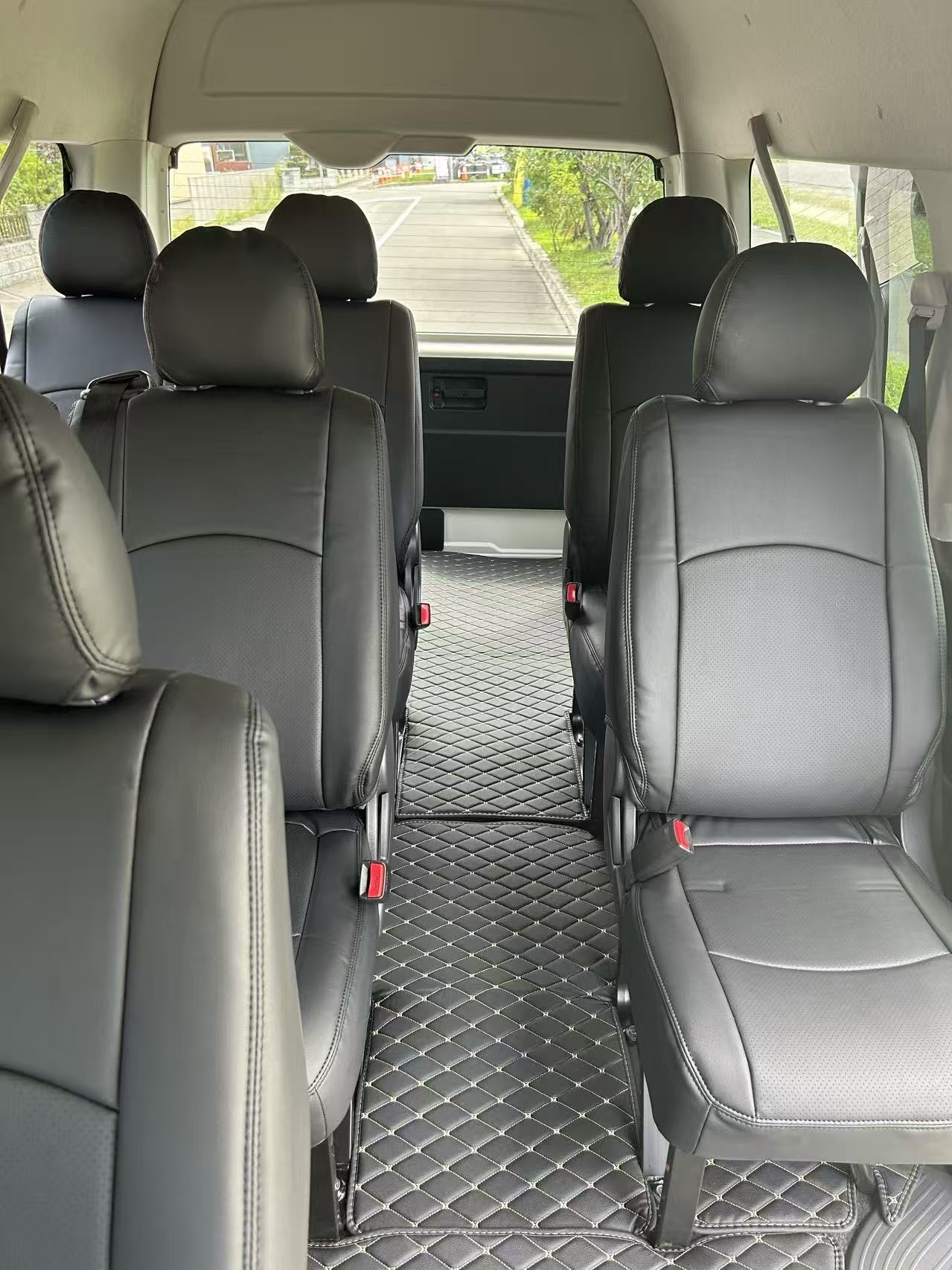 Quilted black-leather cabin of a Toyota Hiace Grand Cabin with diamond-stitched floor mats