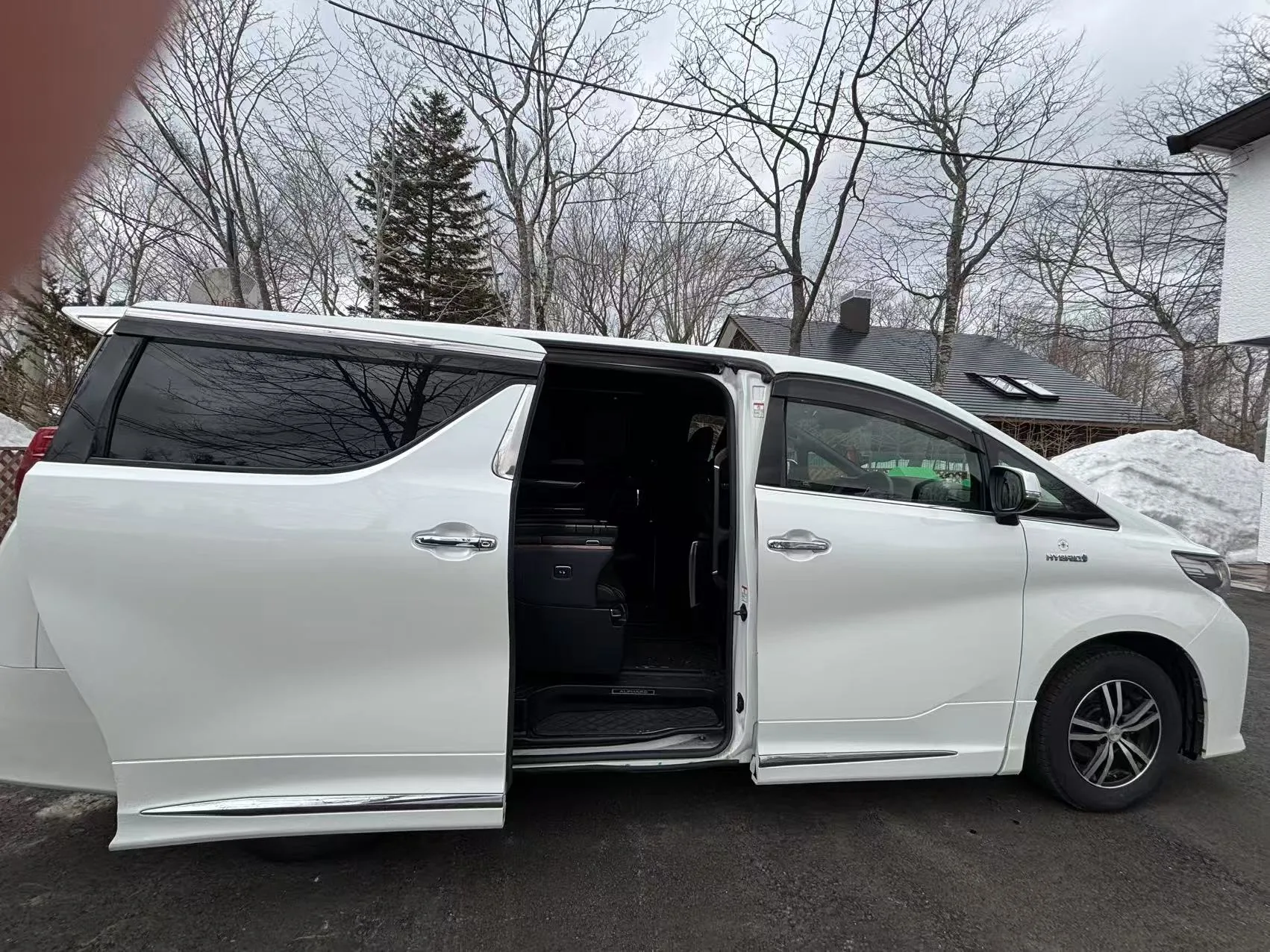 White van with its sliding side door open beside winter snowbanks