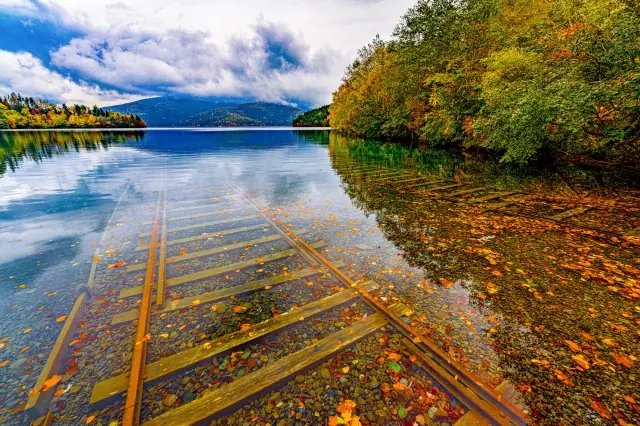 Autumn woodland reflected in clear lake water