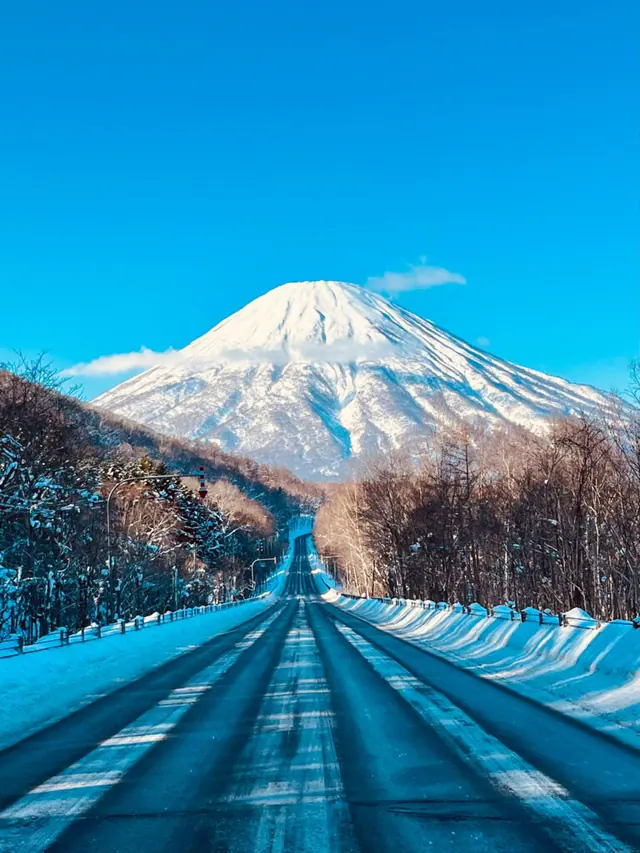 Straight winter road leading toward snow-covered Mt. Yotei in Hokkaido