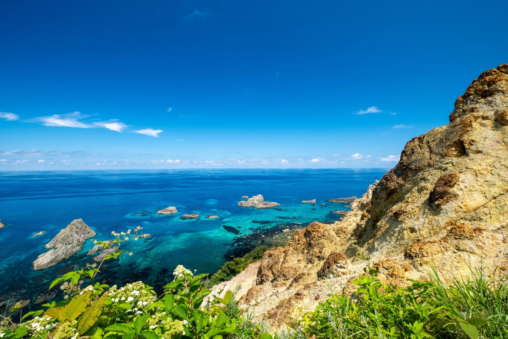 Turquoise 'Shakotan Blue' sea below the rocky cliffs of Cape Kamui on a clear summer day in Hokkaido