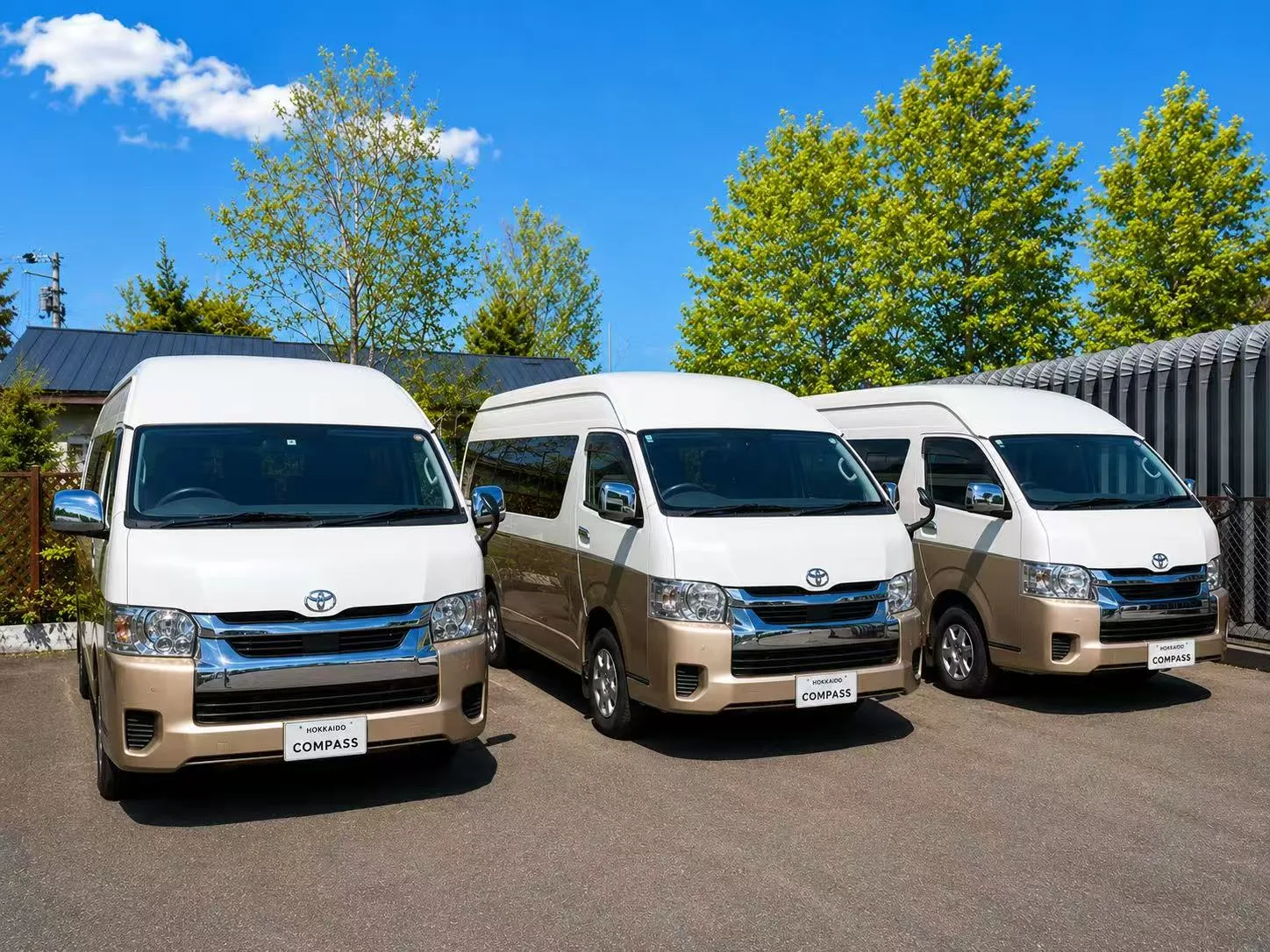 Trio of Hokkaido Compass Toyota Hiace Grand Cabin rental vans lined up under a clear summer sky