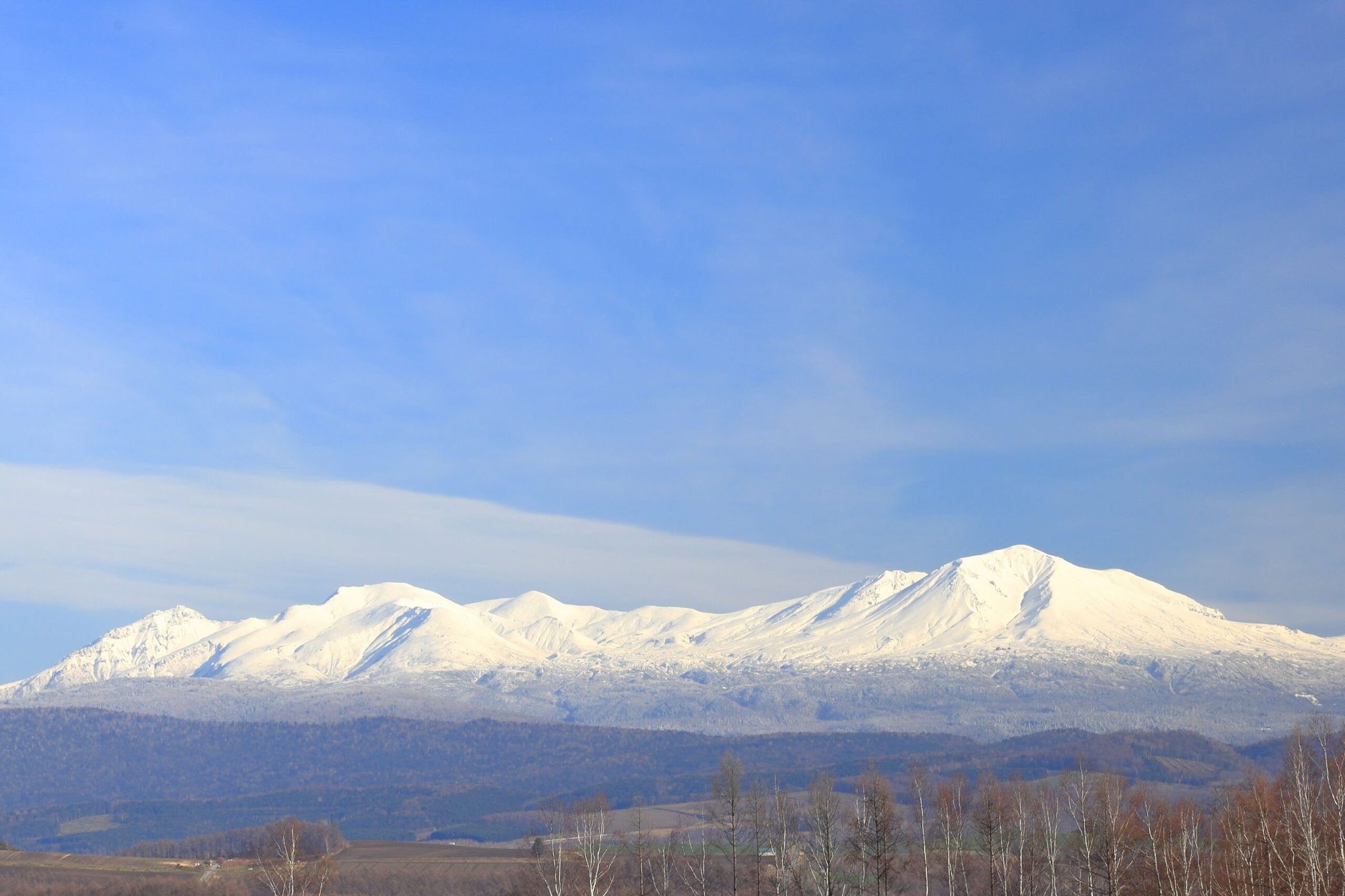 Snow-covered Daisetsuzan mountain range near Asahikawa beneath a blue winter sky