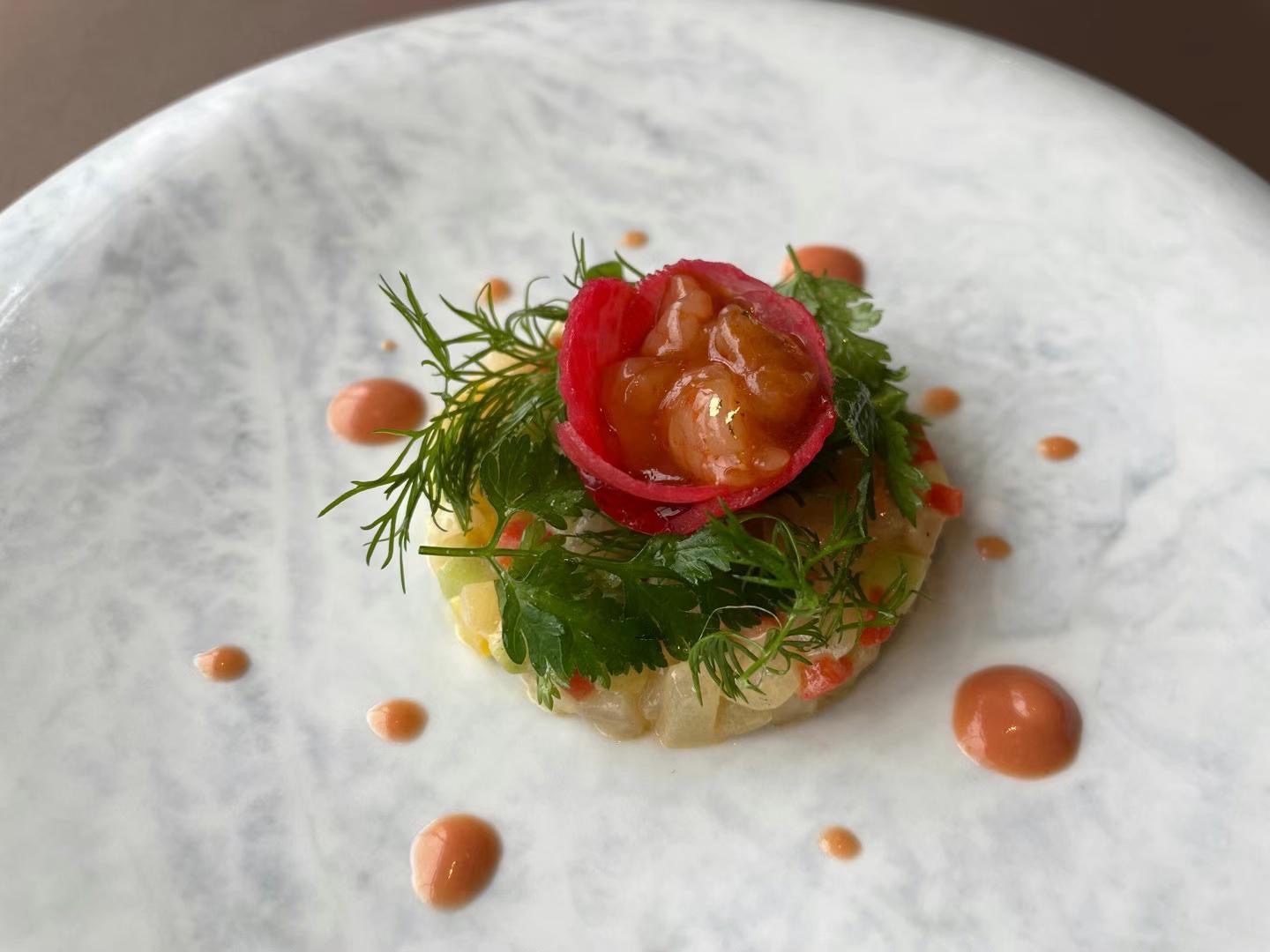 Hokkaido kaiseki amuse with seasonal flower garnish on hand-thrown stoneware