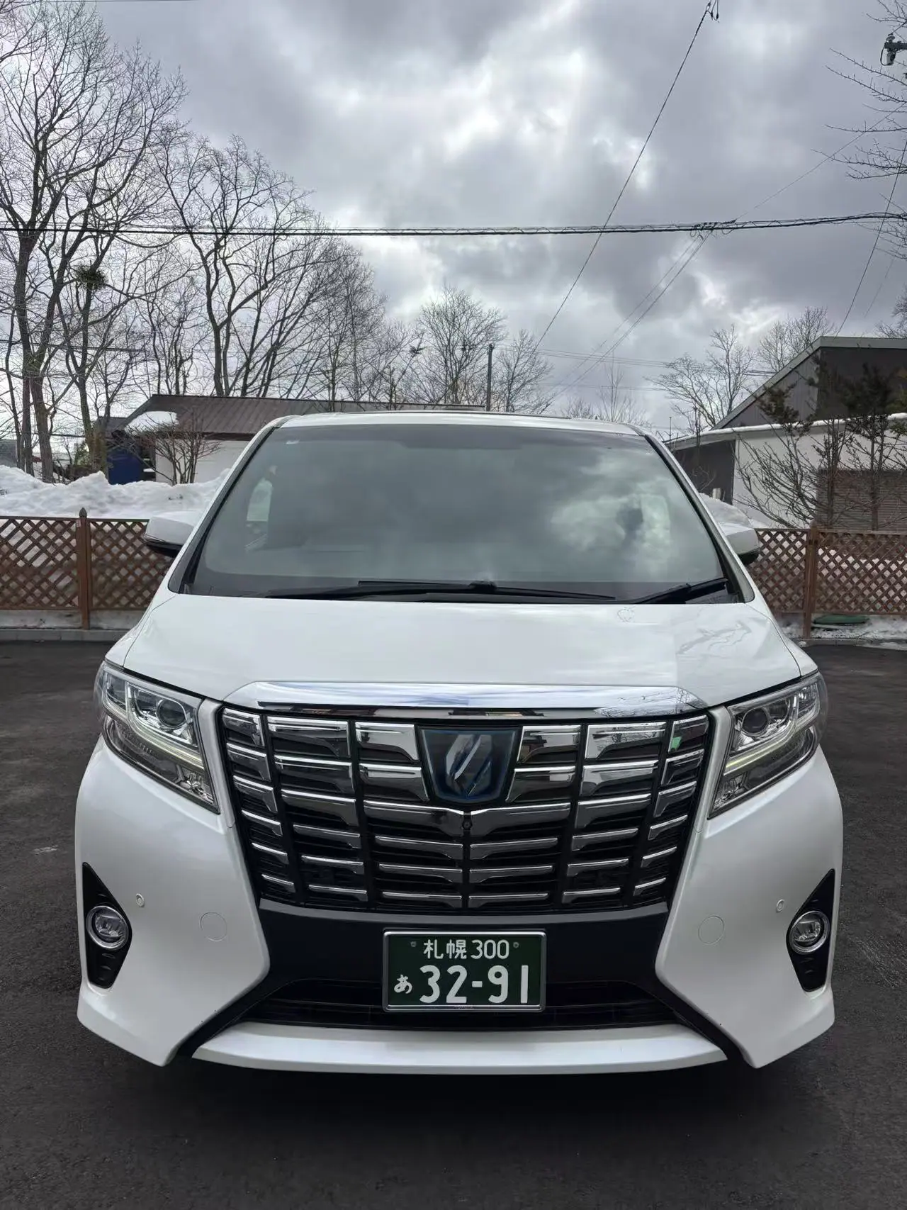 White private vehicle parked on a cleared driveway beside winter snow banks