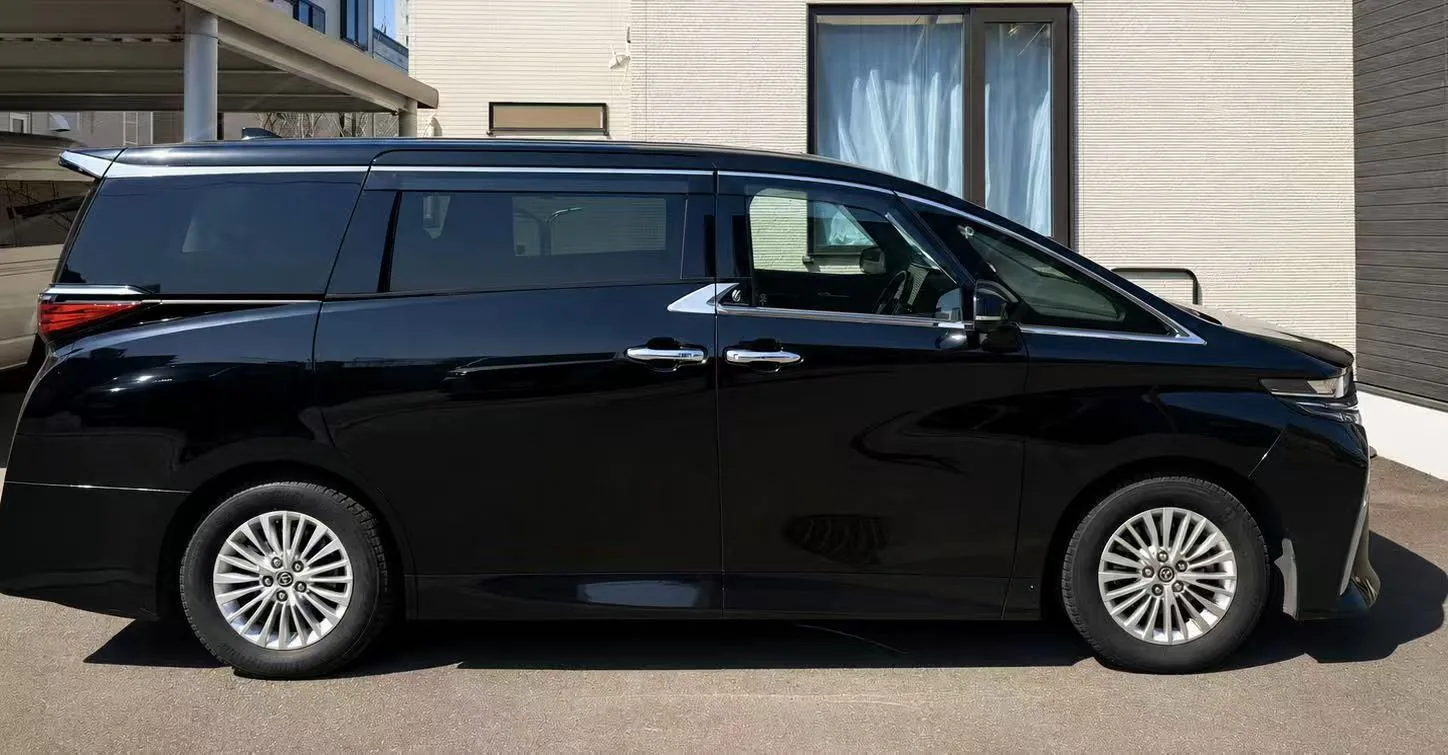 Black Toyota Alphard private charter vehicle in full side profile at a quiet Hokkaido residence