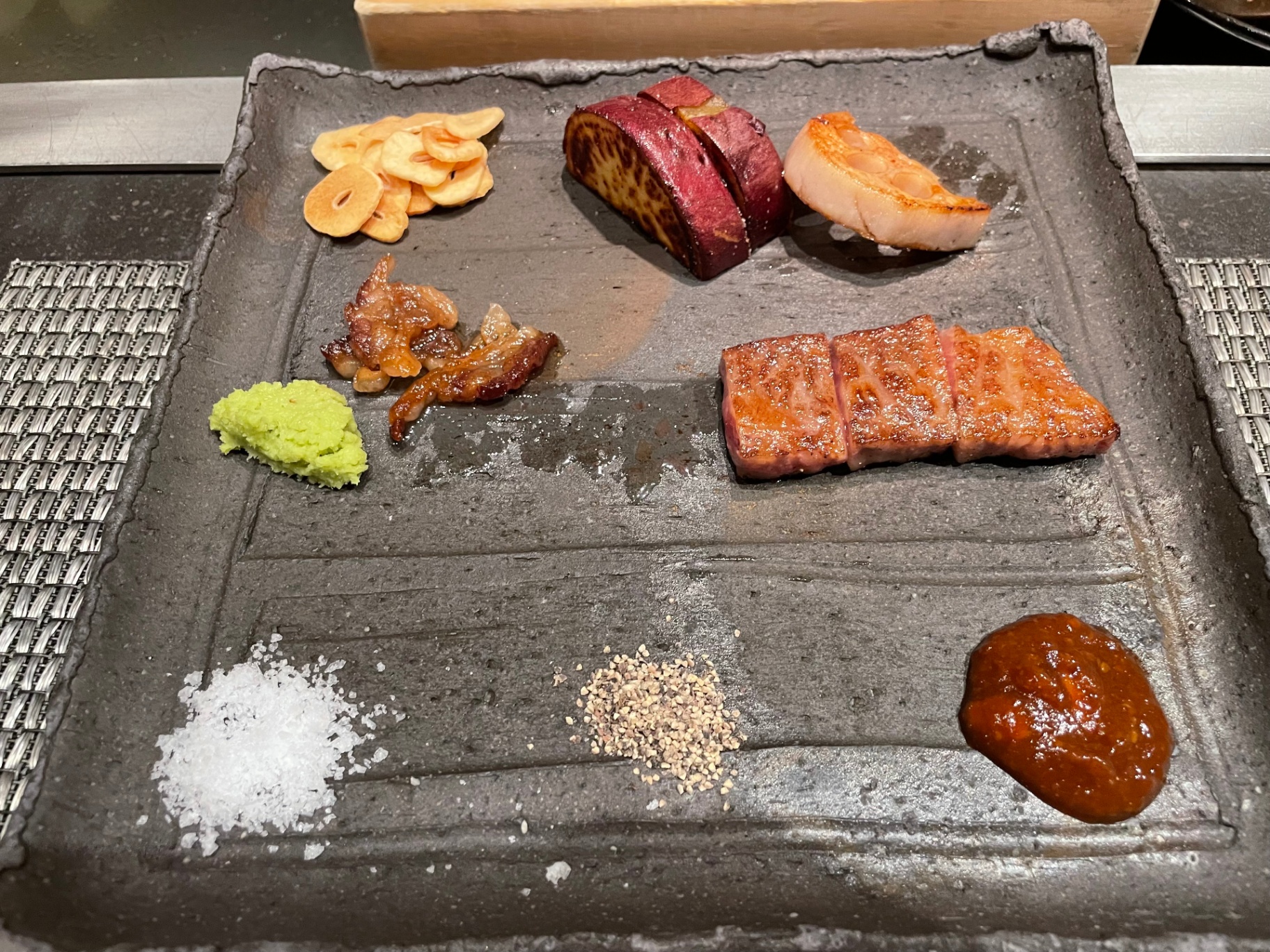 Plated Hokkaido wagyu teppanyaki with garlic chips, lotus root and condiments