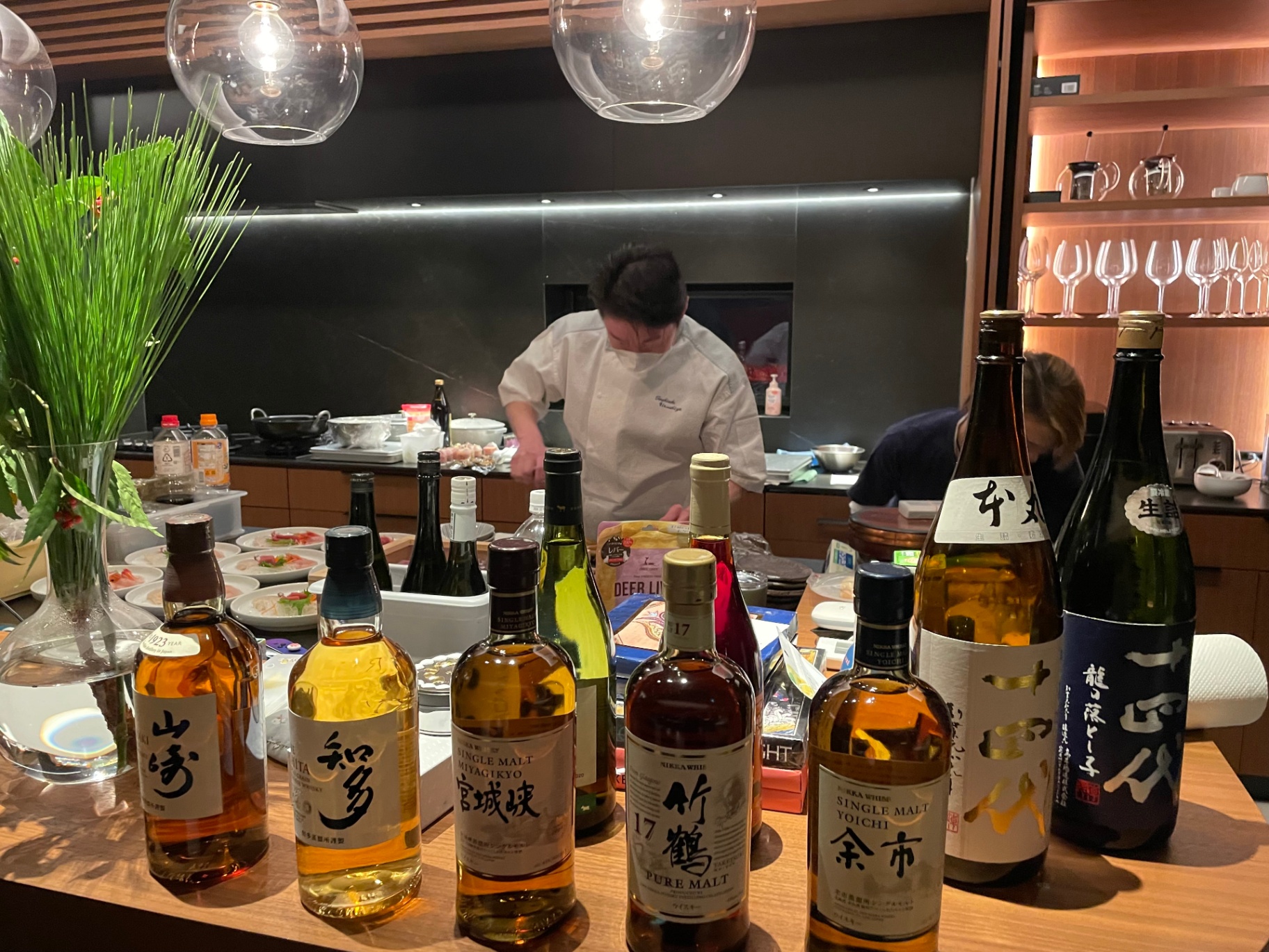 Private chef plating omakase beside a curated Japanese whisky and sake bar