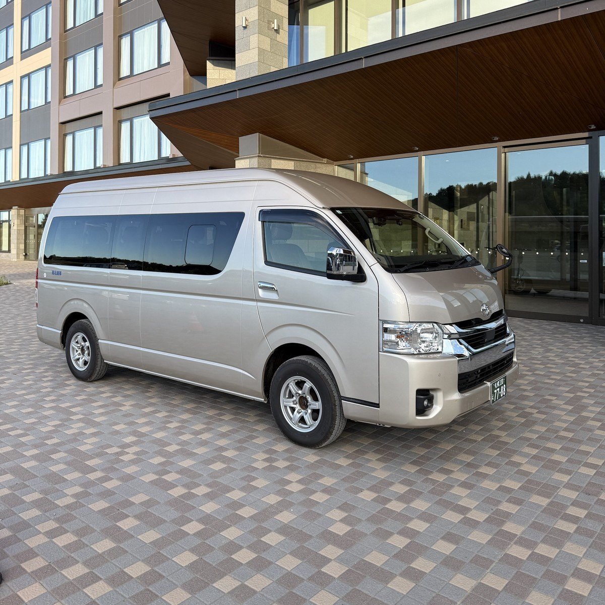 Champagne Toyota Hiace Grand Cabin outside a Hokkaido hotel