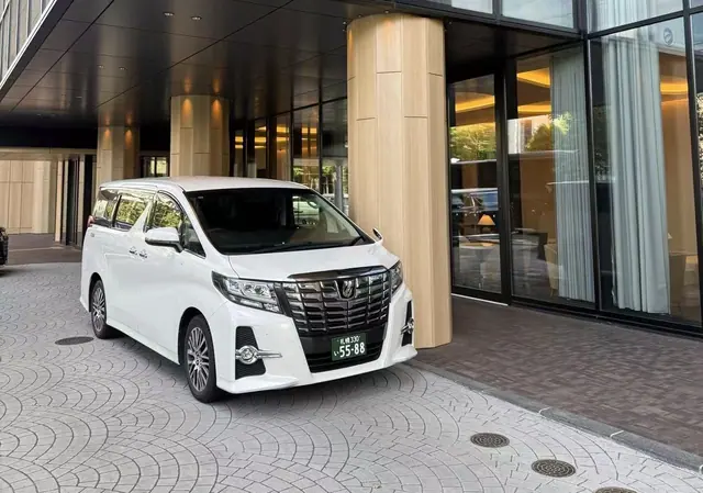 White private van waiting at a hotel entrance