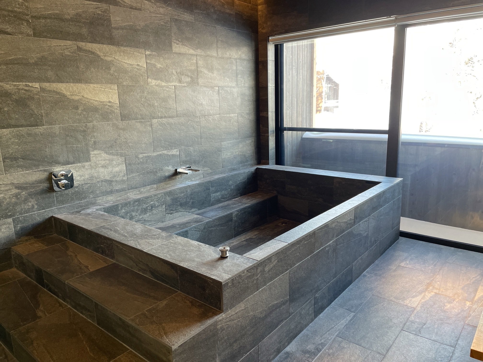 Open-air stone onsen bath framed by birch trees