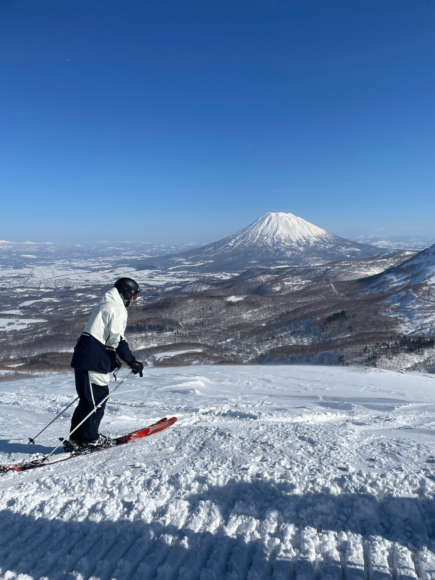 Skier on a quiet Niseko piste with Mt. Yōtei rising across the valley