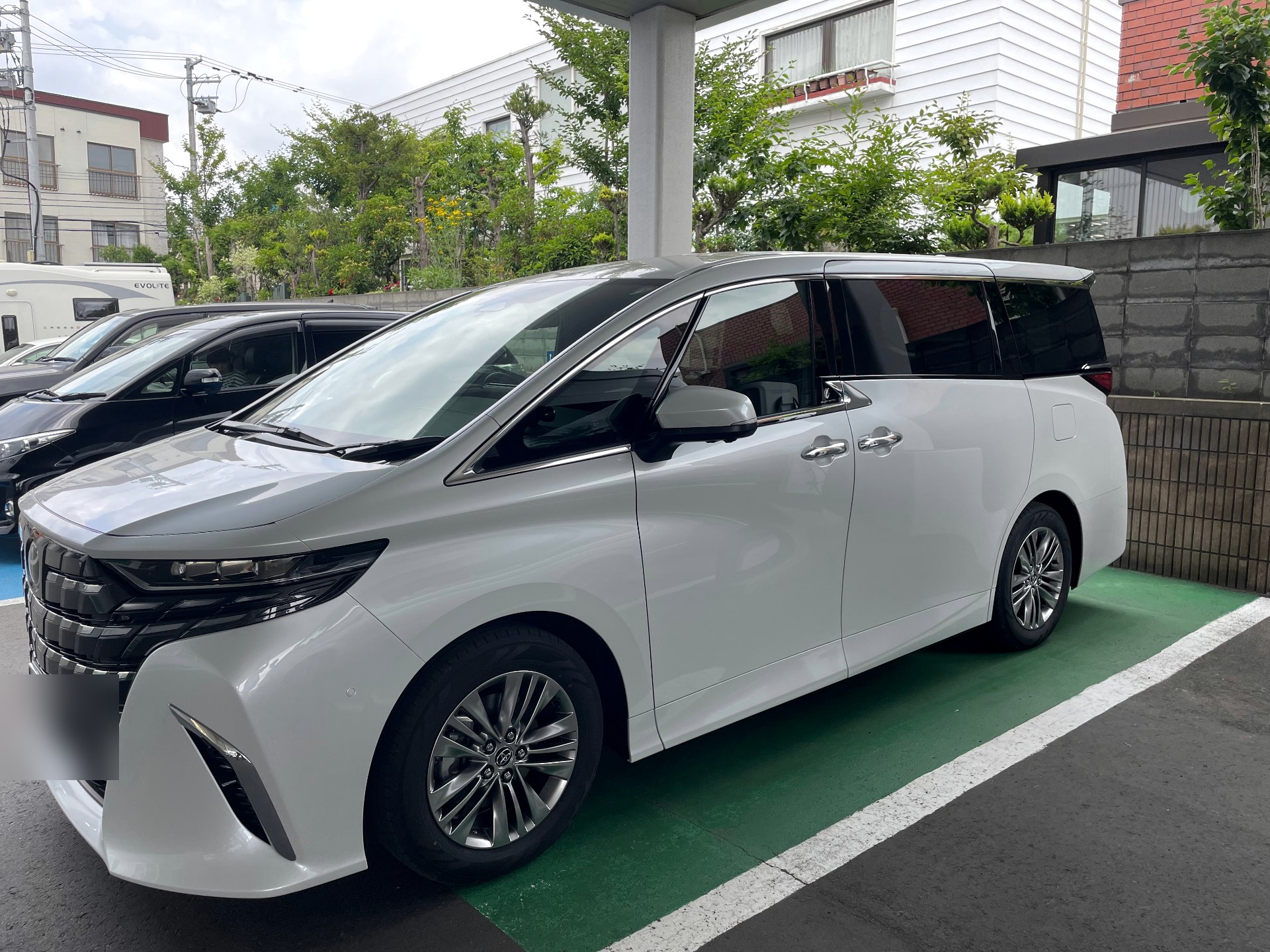 White Toyota Alphard private chauffeur vehicle parked at a quiet Hokkaido residence in summer