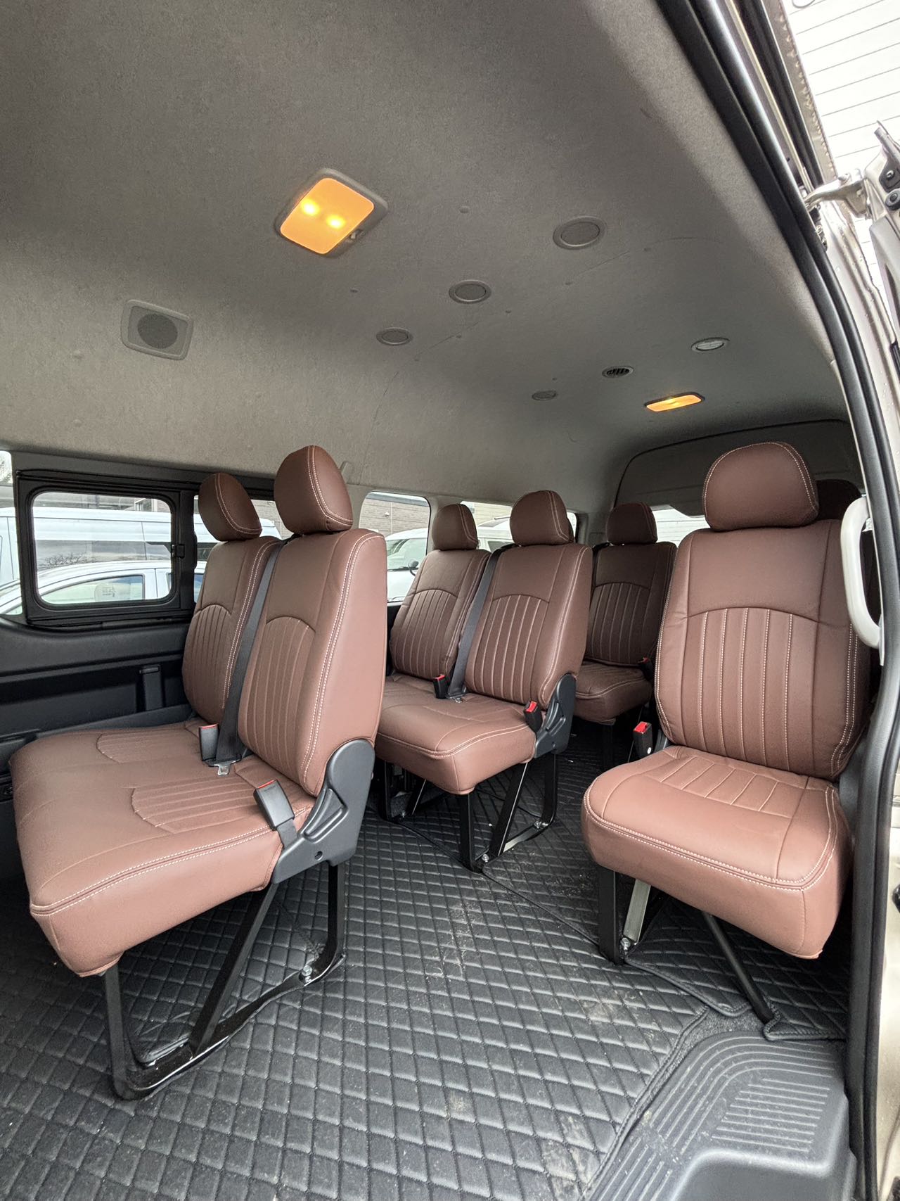 Toyota Hiace Grand Cabin interior with rows of tan leather group seating and quilted floor