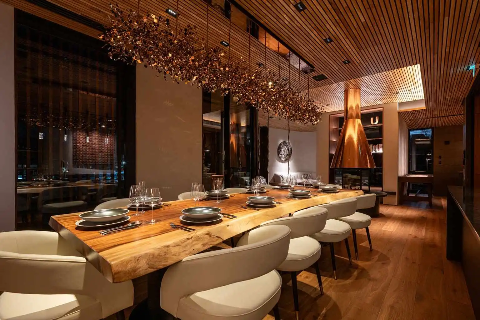 Niseko chalet private dining room with live-edge timber table, copper hood and gilded chandelier