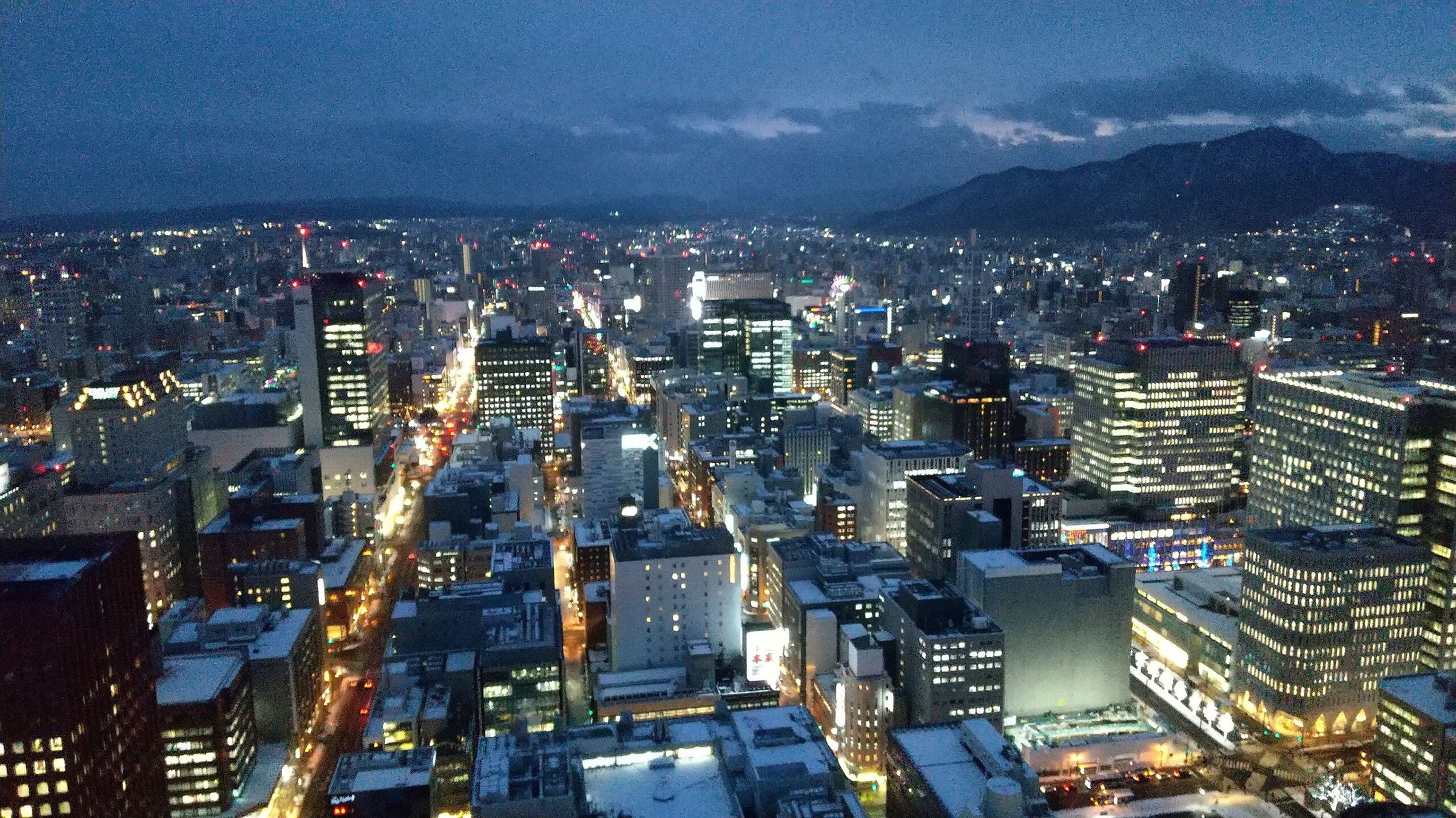 Snow-covered Sapporo streets and city lights at winter twilight