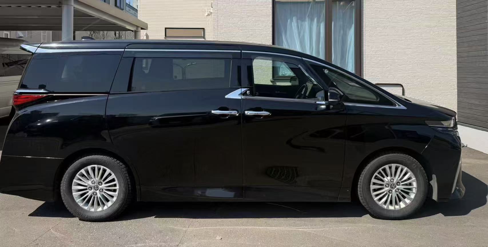 White Toyota Alphard executive transfer vehicle waiting outside a quiet Hokkaido hotel entrance