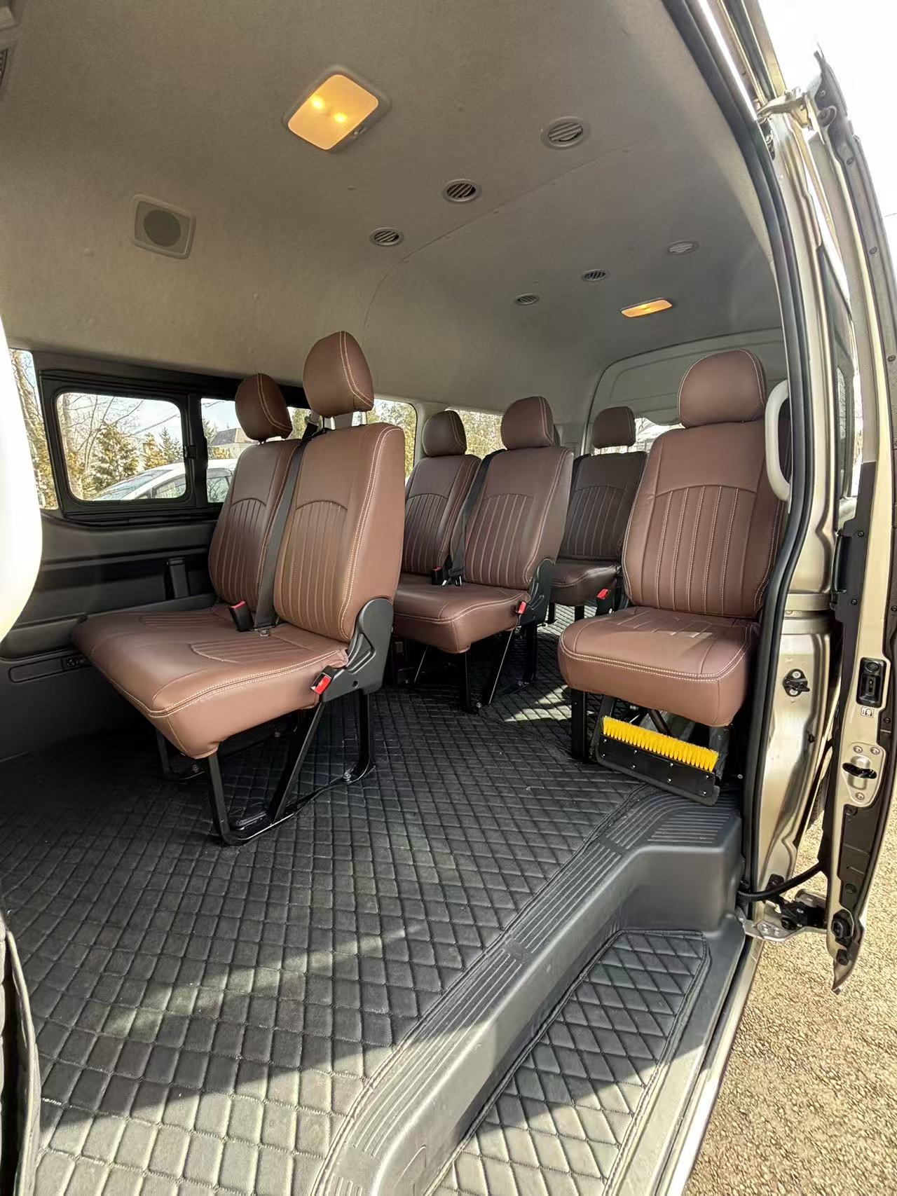 Toyota Hiace Grand Cabin interior with cognac leather rows, quilted floor mats and open side door