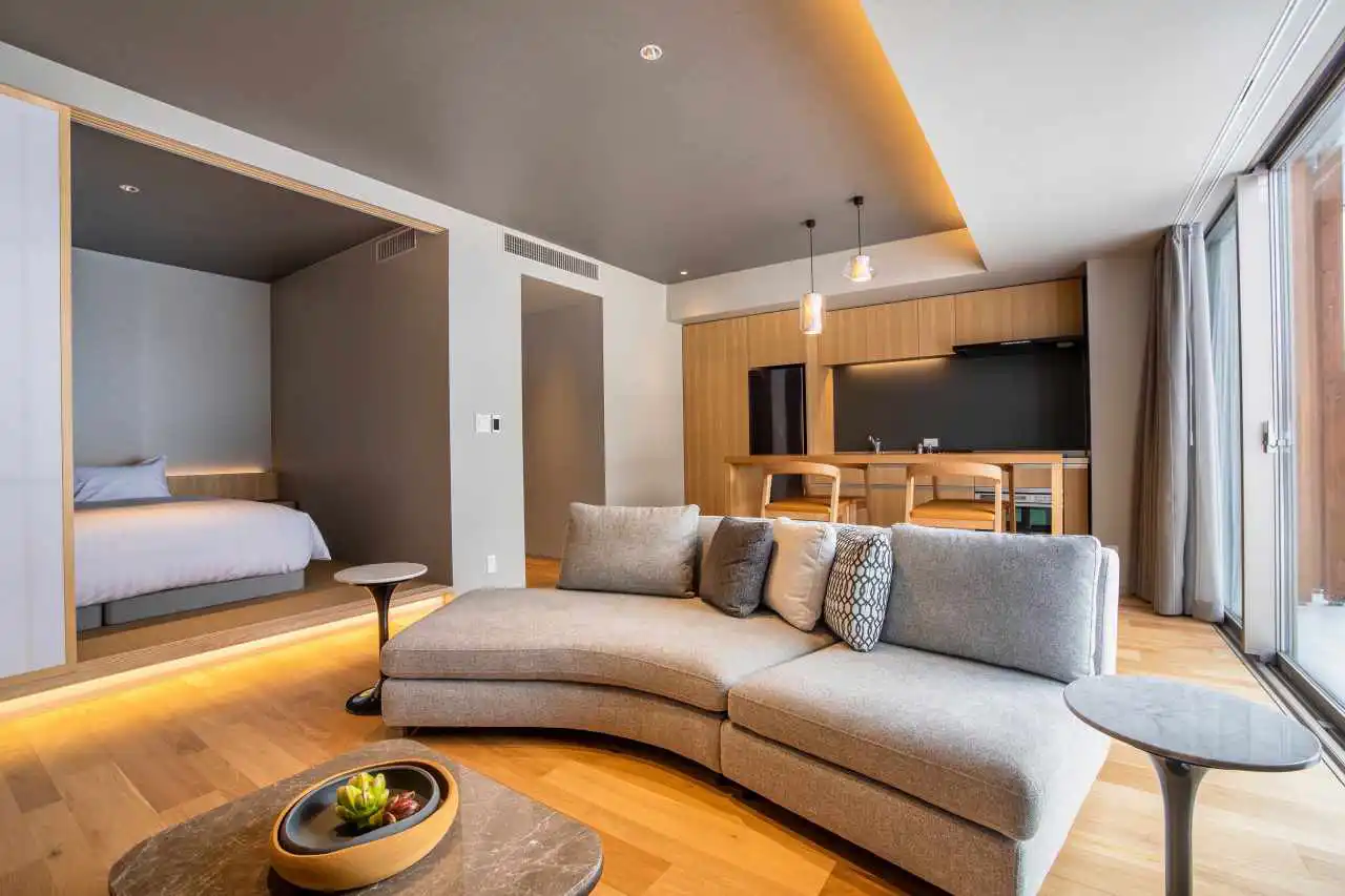 Contemporary luxury suite living room with timber floors and bedroom beyond