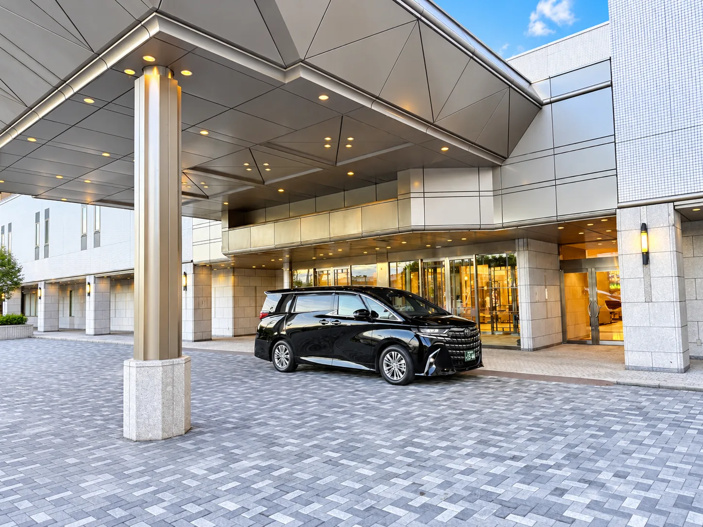 Black private van under a hotel entrance canopy