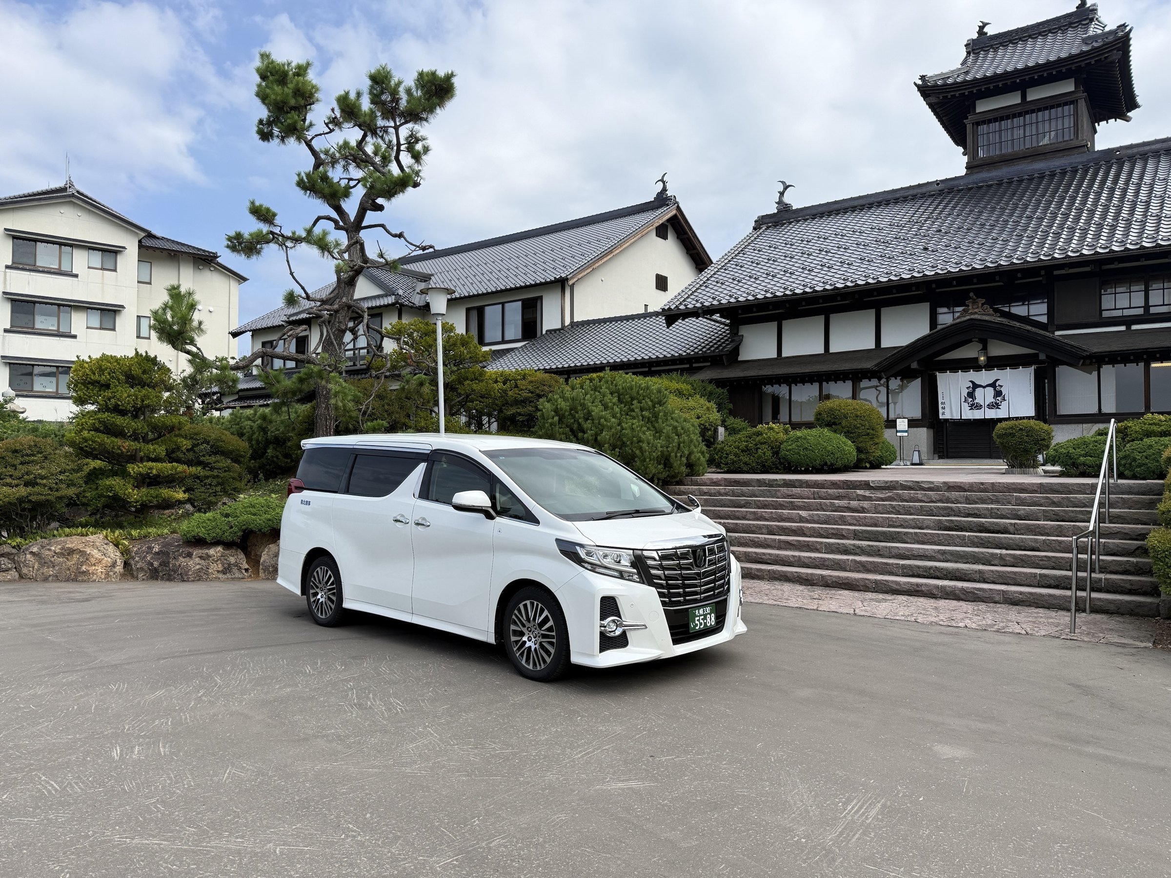 White Toyota Alphard in front of a traditional Japanese building in Hokkaido