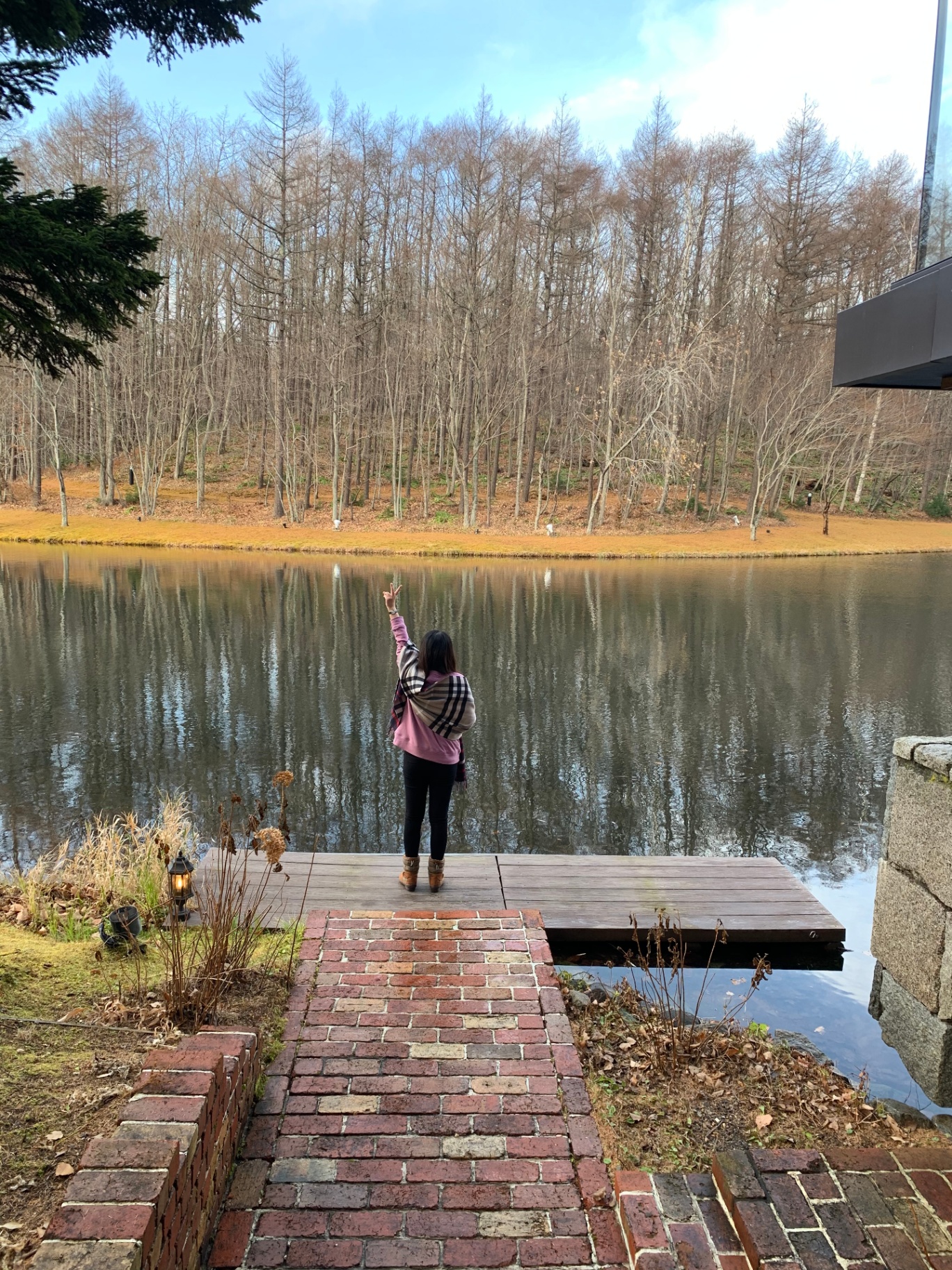 Guest standing by a quiet lake at a Hokkaido resort in autumn