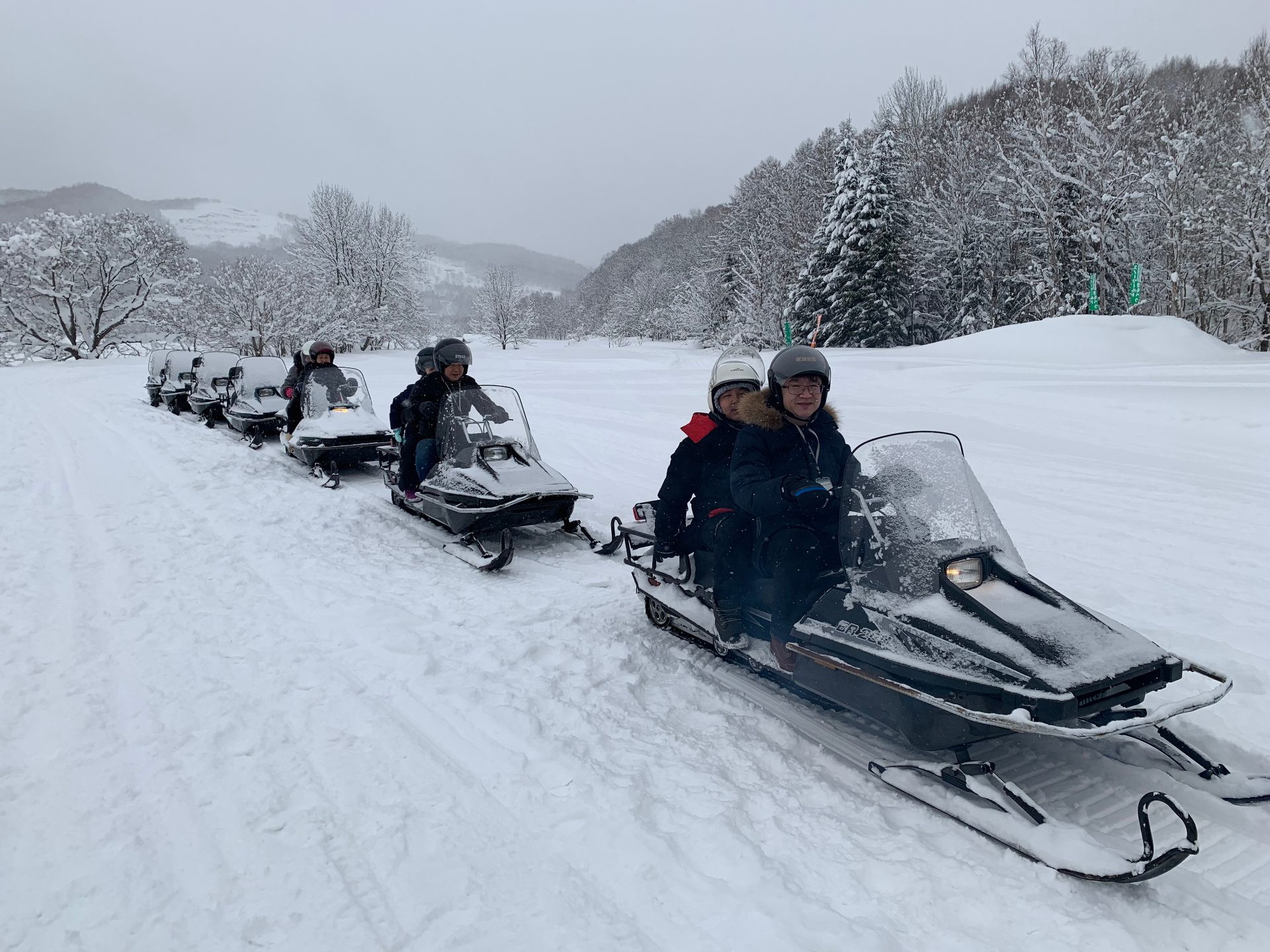 Snowmobile tour line on fresh powder above Niseko
